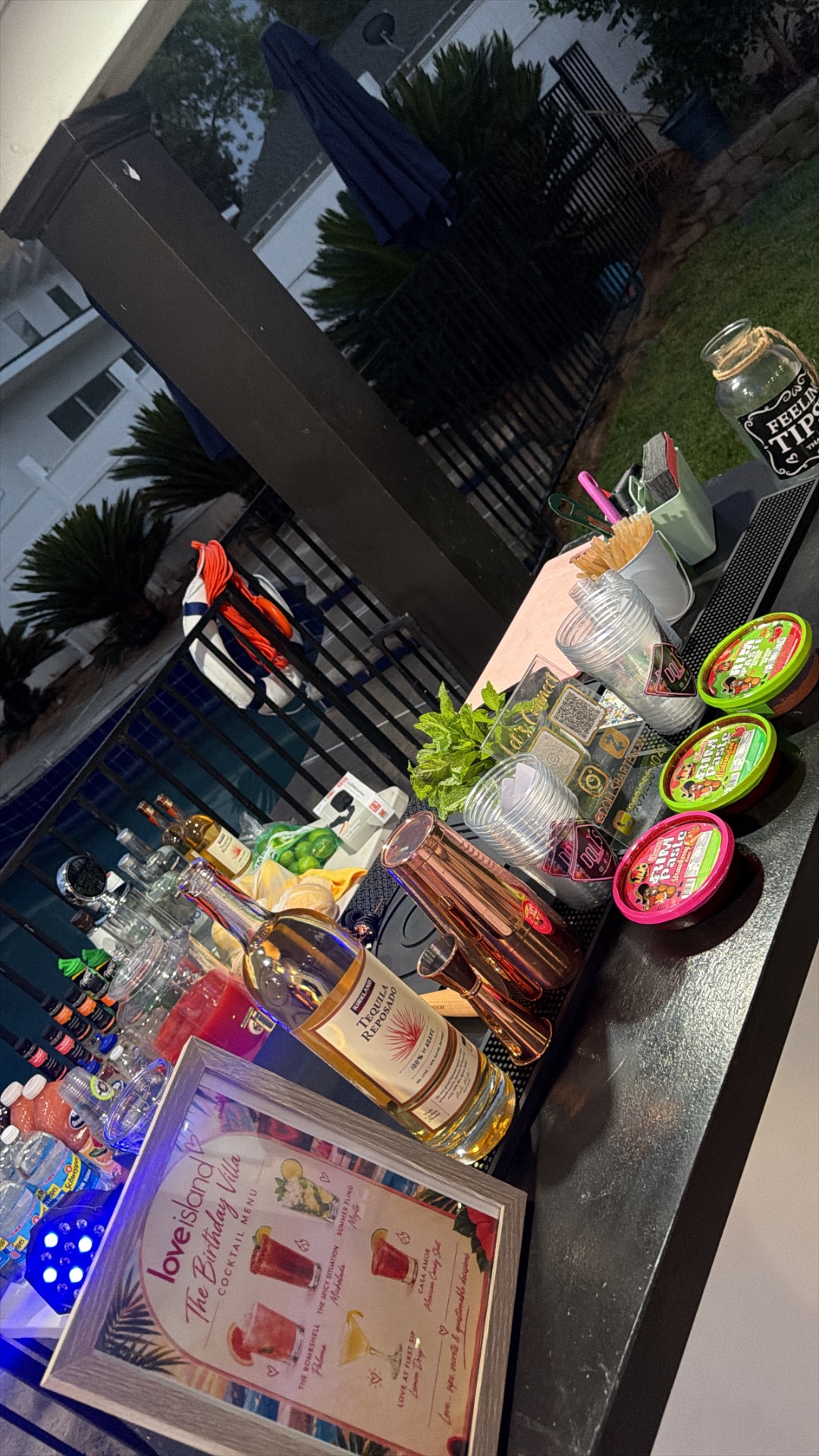 Dolls Bartending printed cocktail menu, liquors, and bar tools at a Love Island themed birthday party