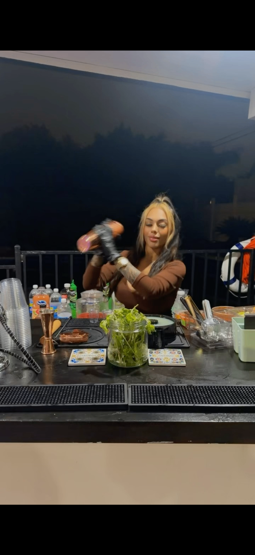 Dolls Bartending bartender in gloves shaking a cocktail behind the bar at night